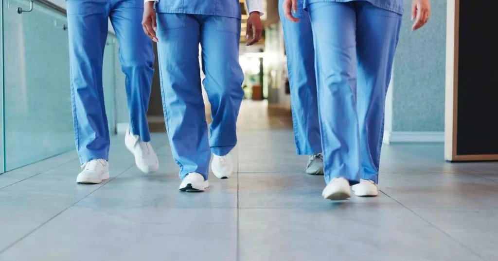 Healthcare professionals walking together in a hospital wearing cushioned, supportive shoes to reduce foot pain and prevent workplace injury.