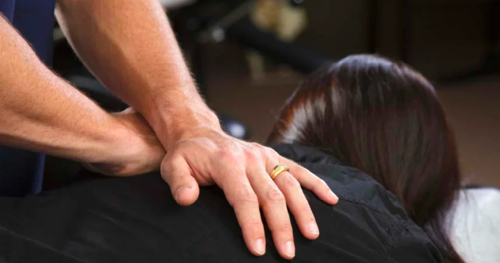 Chiropractor placing hands on a patient’s back during an adjustment, demonstrating how chiropractic care helps healthcare workers prevent and treat injuries.