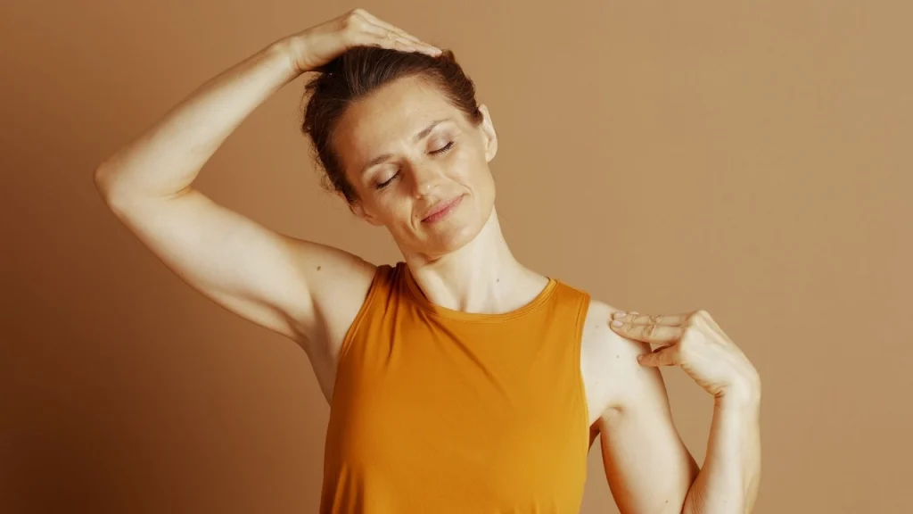 A woman holds her head and shoulder as she stretches her head to the side